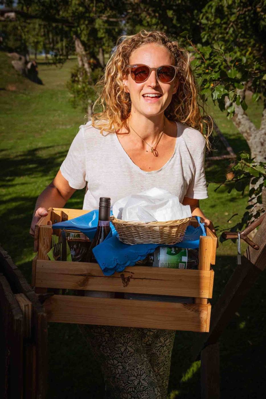 Lächelnde Frau bringt die Frühstücksbox zum Häusle bei der Linde