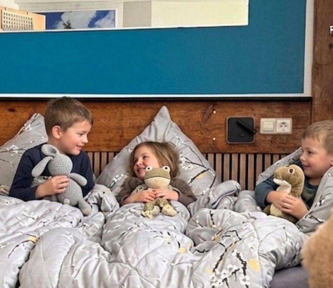 Kinder kuscheln im Bett im Kinderzimmer der Ferienwohnung Magaritte