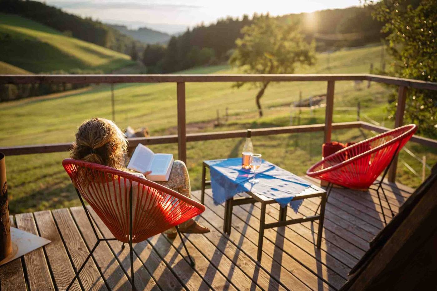Frau liest auf der Terrasse des Häusle bei der Linde mit Blick ins Grüne
